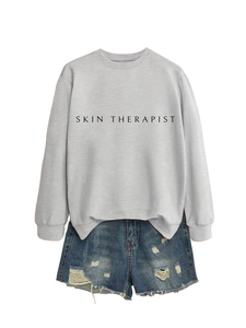 Détail du sweat-shirt gris à col rond Skin Therapist avec un short en jean délavé
