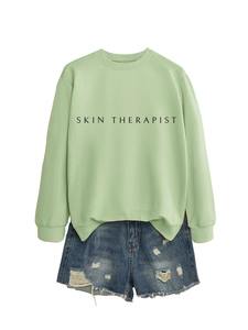 Détail du sweat vert clair Skin Therapist avec poignets côtelés et short en jean