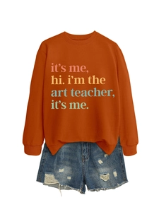Close-up of orange sweatshirt with it's me hi i'm the art teacher colorful print