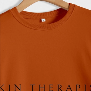 Sweatshirt orange minimaliste avec imprimé Skin Therapist sur tissu en coton doux