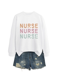Flat lay of white nurse-themed sweatshirt with colorful lettering and denim shorts