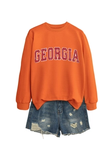 Detail of Georgia print on orange crewneck sweatshirt paired with frayed denim shorts