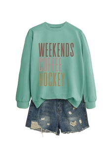 Flat lay of mint green weekends coffee hockey sweatshirt with distressed denim shorts
