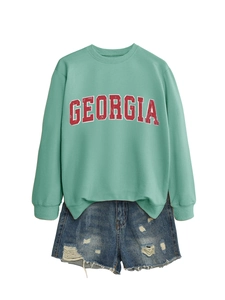 Flat lay of a mint green Georgia crewneck sweatshirt paired with distressed denim shorts