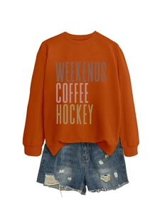 Close-up of orange Weekends Coffee Hockey sweatshirt paired with distressed denim shorts