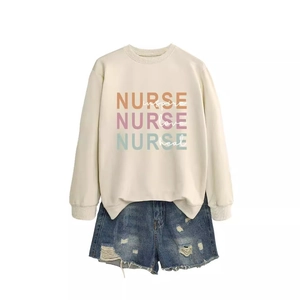 Flat lay of cream Nurse sweatshirt with colorful lettering and ripped denim shorts