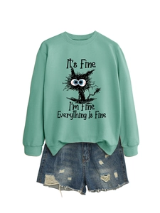 Close-up of mint green sweatshirt with 'It's Fine' cat print and ripped denim shorts