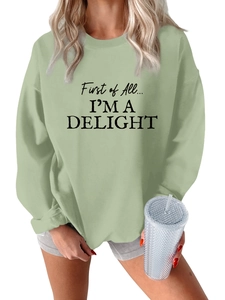 Close-up of black slogan lettering on light green oversized warm crewneck sweatshirt