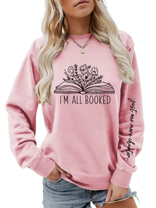 Détail montrant le texte 'I'M ALL BOOKED' et l'imprimé sur sweat rose à manches longues