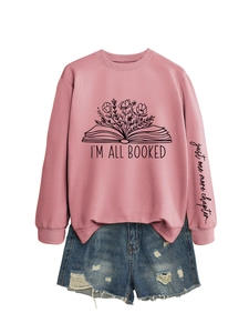 Détail du sweat rose avec texte 'I'M ALL BOOKED' et imprimé floral de livre sur le buste