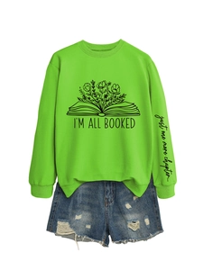 Détail du sweat-shirt vert avec motifs floraux et texte I'm all booked sur le devant