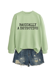 Détail du sweat-shirt vert clair avec texte 'Basically a Detective' et short en jean