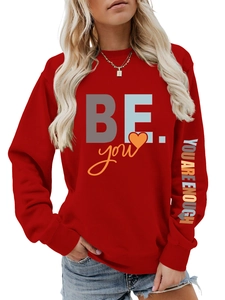 Détail du sweat rouge avec l'imprimé 'YOU ARE ENOUGH' multicolore sur la manche gauche