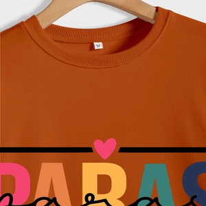 Close-up of caramel orange sweatshirt collar with DABAS print and pink heart detail