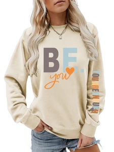 Détail du sweat-shirt beige avec imprimé coloré sur la manche et motif sur la poitrine