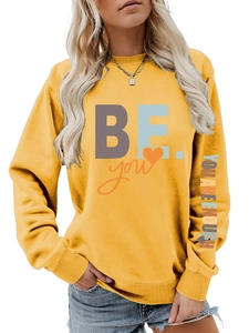 Détail du slogan YOU ARE ENOUGH et des poignets côtelés sur le sweat-shirt jaune gingembre