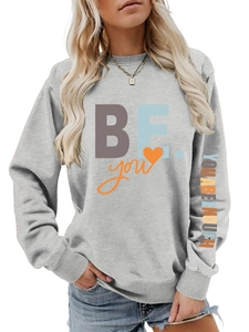 Détail de l'inscription 'YOU ARE ENOUGH' sur la manche d'un sweat-shirt gris