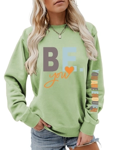 Détail du sweat vert avec imprimé BE YOU et texte YOU ARE ENOUGH sur la manche
