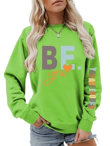 Détail d'un sweat vert vif avec texte coloré sur la manche et imprimé graphique