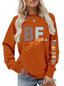 Détail de l'imprimé 'YOU ARE ENOUGH' sur la manche d'un sweat orange à manches longues