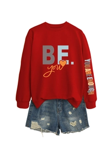 Détail du sweat rouge avec impression 'YOU ARE ENOUGH' sur la manche et logo cœur