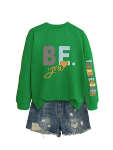 Détail du sweat vert avec imprimé YOU ARE ENOUGH sur la manche et short en jean bleu
