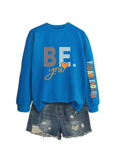 Détail du sweat bleu avec imprimé sur la manche et short en jean délavé usé