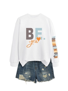 Détail du sweat-shirt blanc avec manche imprimée et mini short en jean bleu déchiré