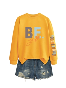 Détail de l'imprimé manche 'YOU ARE ENOUGH' sur sweat orange et short en jean vieilli