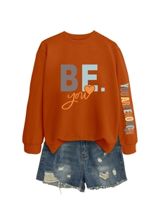 Détail du sweat orange avec imprimé BE you et slogan coloré brodé sur la manche gauche