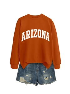 Flat lay of an oversized orange Arizona sweatshirt paired with ripped denim shorts