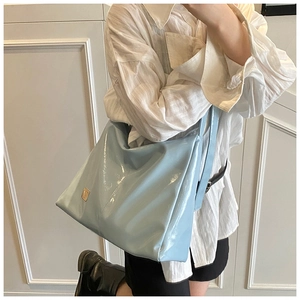 Close-up of light blue patent leather tote bag with glossy finish and metal detail