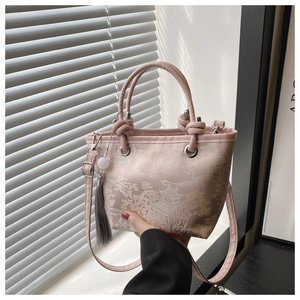 Close-up of pink brocade bucket bag featuring traditional Chinese embroidery and tassel