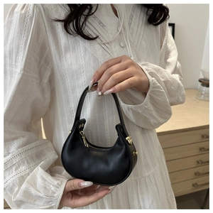 Détails du sac demi-lune noir montrant la texture du cuir et les ferrures dorées de luxe