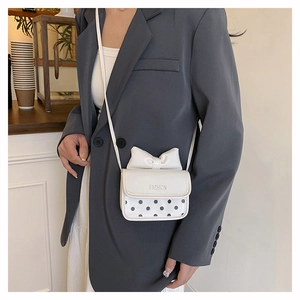 Détail du sac bandoulière blanc avec nœud et pois noirs porté par un mannequin de mode