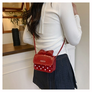 Détail d'un mini sac bandoulière rouge avec nœud décoratif et motif à pois tendance