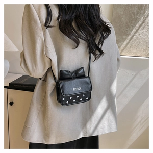 Gros plan d'un sac bandoulière noir à nœud avec pois blancs et lettrage FASHION