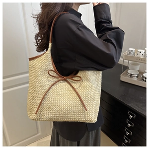 Detail of straw tote bag featuring contrast dark brown trim and slender bow decoration