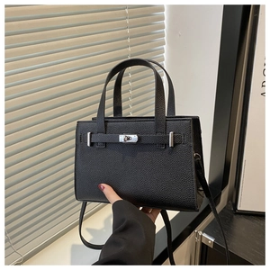 Detail of black pebbled leather tote featuring silver metal twist lock and texture
