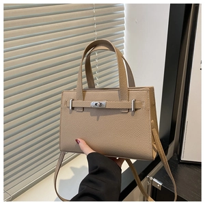 Close-up of lychee grain leather handbag featuring silver twist lock and strap detail