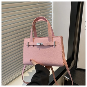 Detail of pink lychee leather handbag with silver twist lock and chic belt strap