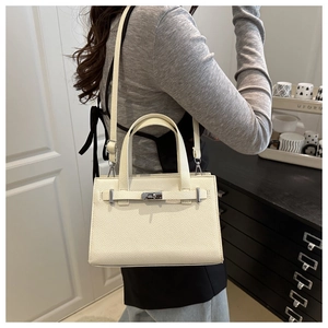 Side view of cream tote bag with silver turn-lock and leather texture on a model