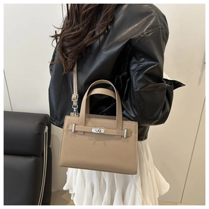 Close-up of beige litchi grain leather tote bag with silver hardware on a fashion model