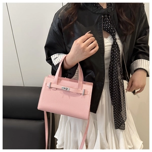Pink litchi grain leather bag with metal turn-lock, shown on a model with a black leather jacket