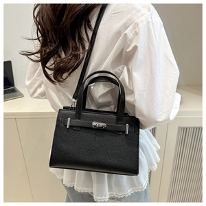 Black pebbled leather handbag with silver rotary lock and shoulder strap on model