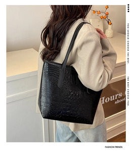 Close-up of black crocodile pattern tote bag showing textured faux leather and long straps