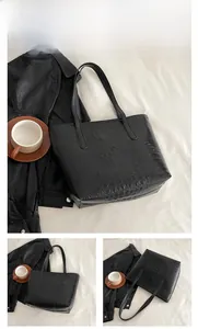 Close-up of black tote bag with crocodile texture and long shoulder straps detail