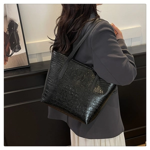 Close-up of black crocodile pattern tote bag showing glossy texture and shoulder strap