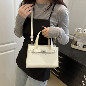 White lychee leather shoulder bag with silver turn-lock and adjustable strap in room