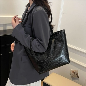 Fashionable black crocodile embossed tote bag for women showing a stylish shoulder carry